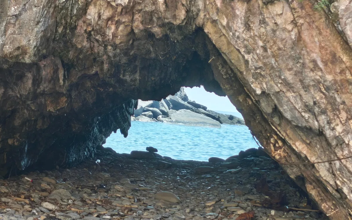 The sea seen through a rock arch on a pebble shore