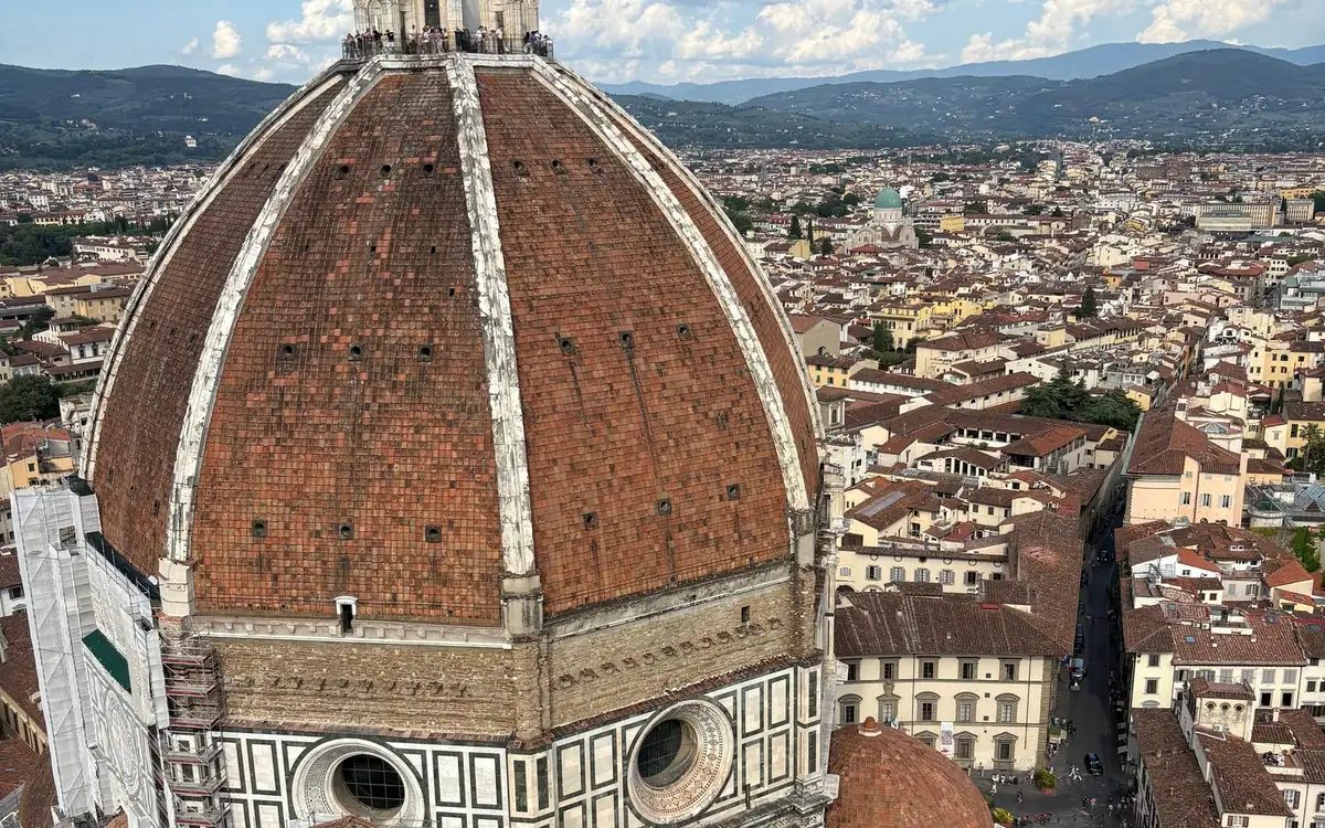 The red-brick dome with white ribs seen from above, visitors on the terrace at the top