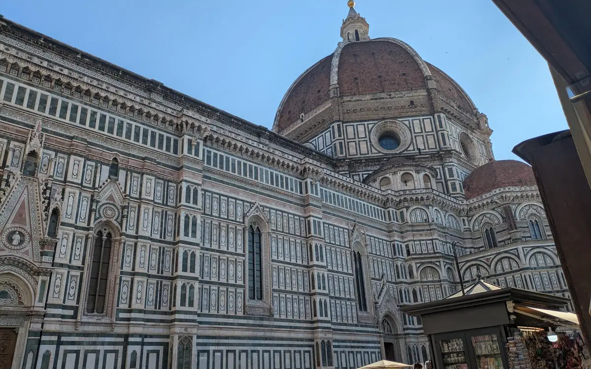 The side of Florence Cathedral in white, green and pink marble, the red-brick dome rising behind it
