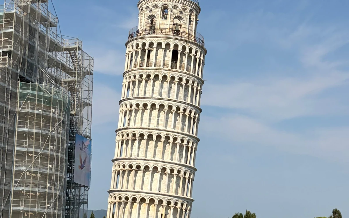 The Leaning Tower of Pisa beside a building wrapped in scaffolding