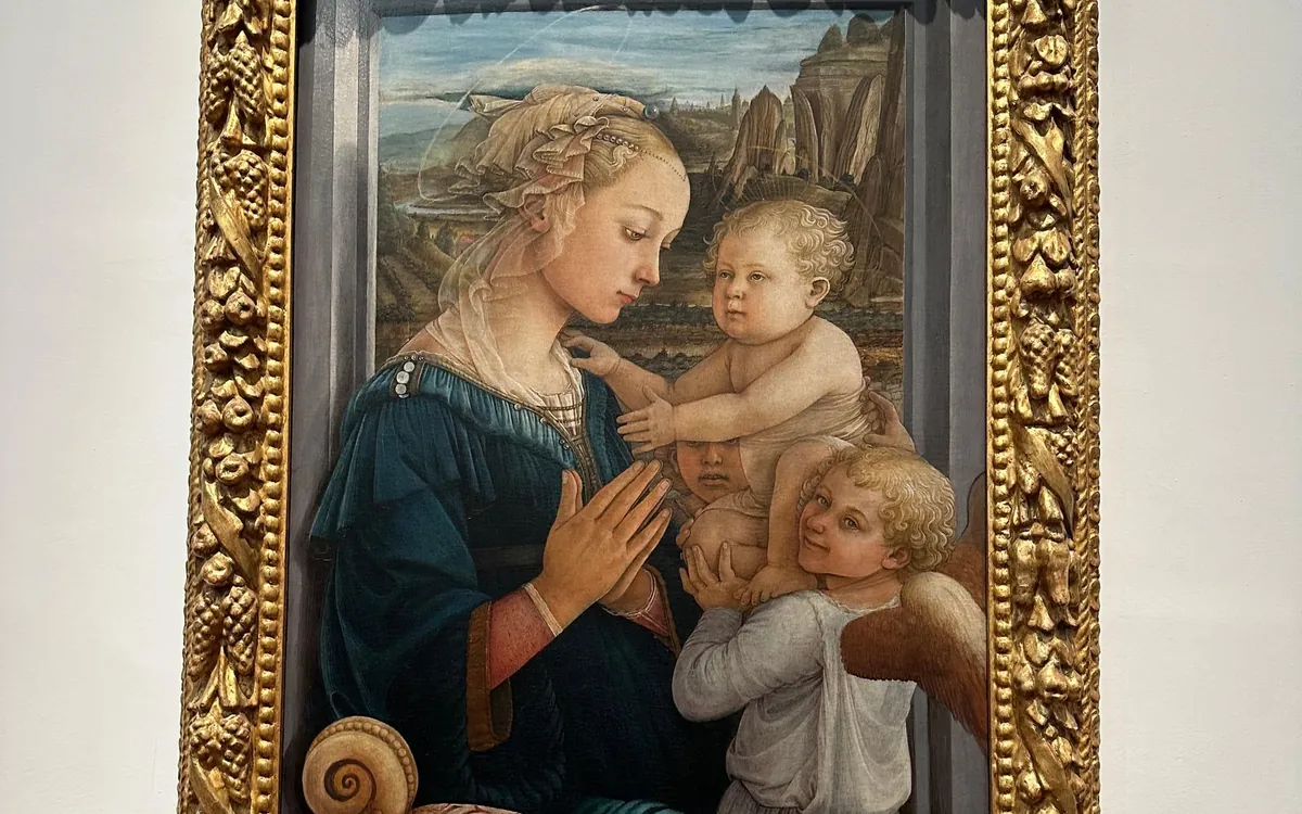 A Madonna and Child with two angels in a carved gold frame