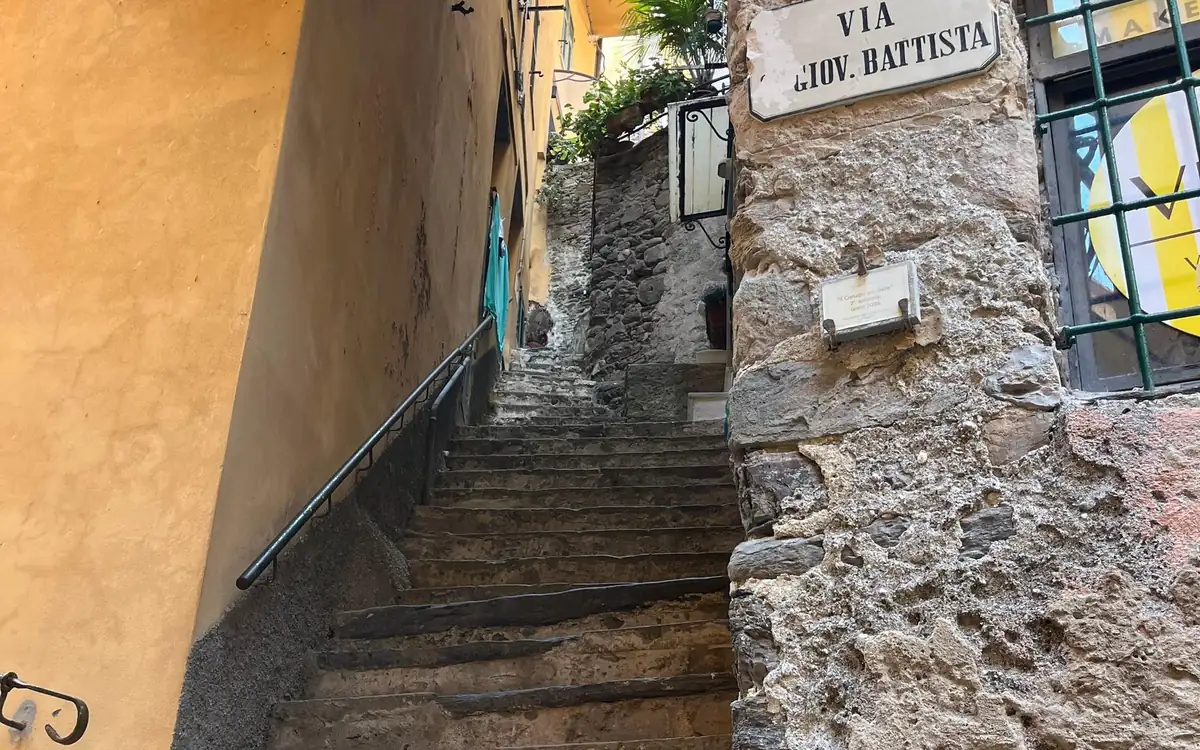 A narrow stepped lane climbing between an ochre wall and a stone wall