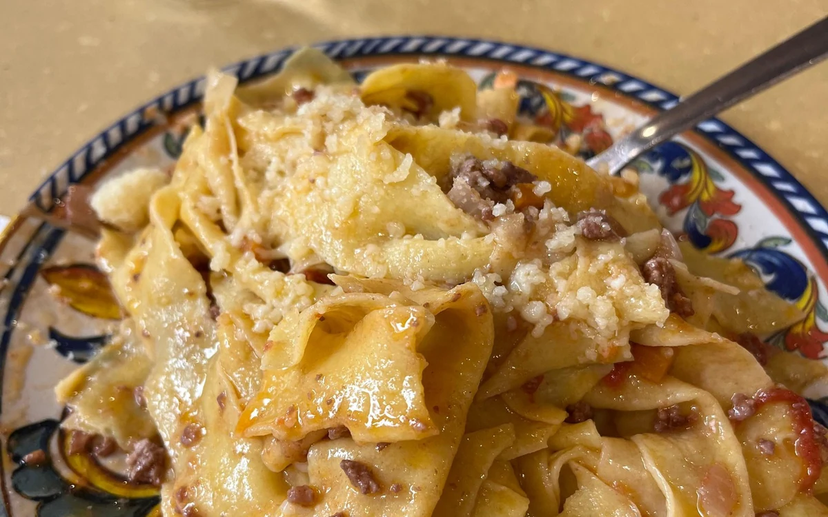 Ribbon pasta with meat ragù on a hand-painted plate