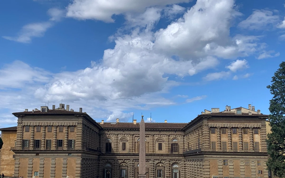 The rusticated stone front of the Pitti Palace under a cloudy sky