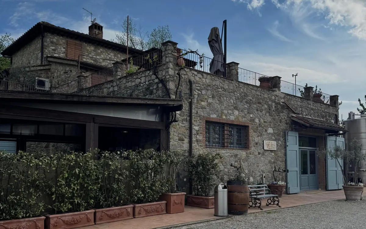 A stone farmhouse with blue shutters, terracotta pots and a bench by the door