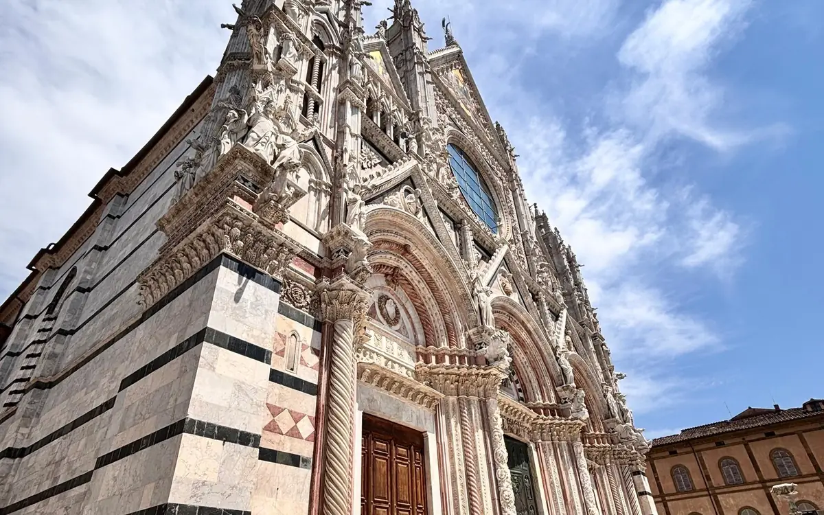The striped marble front of the cathedral in Siena, seen from below