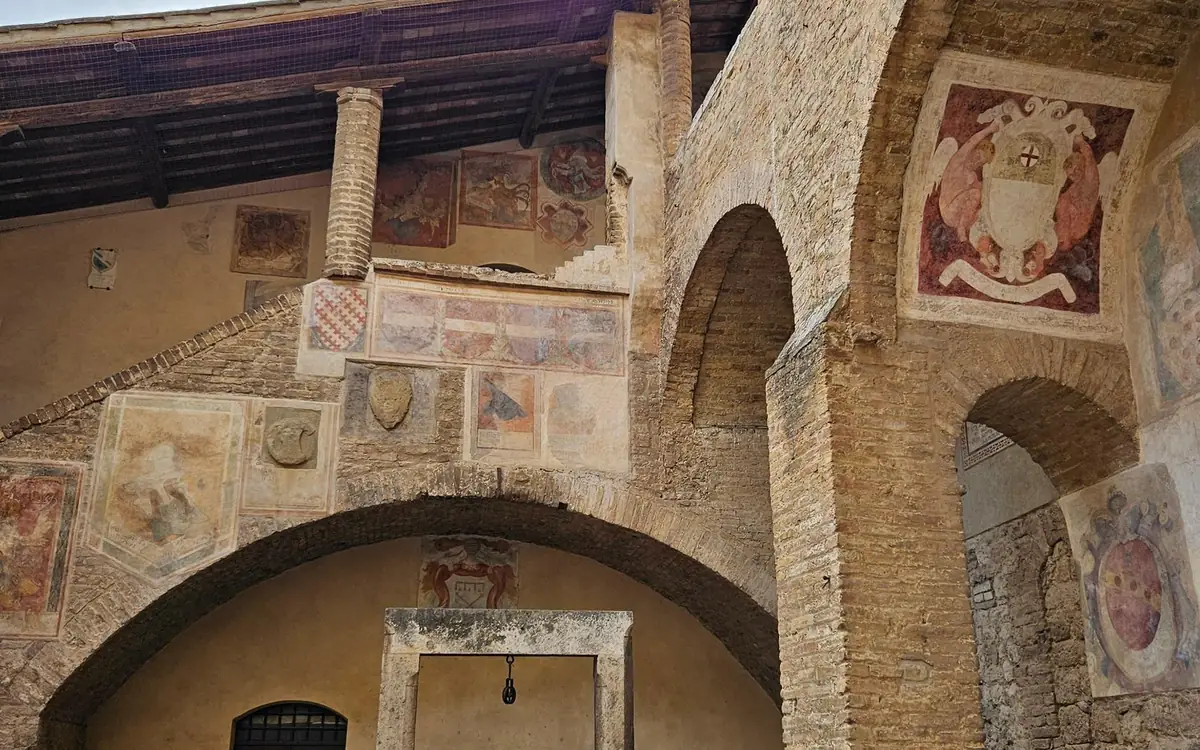 Painted coats of arms on the brick walls of a medieval courtyard