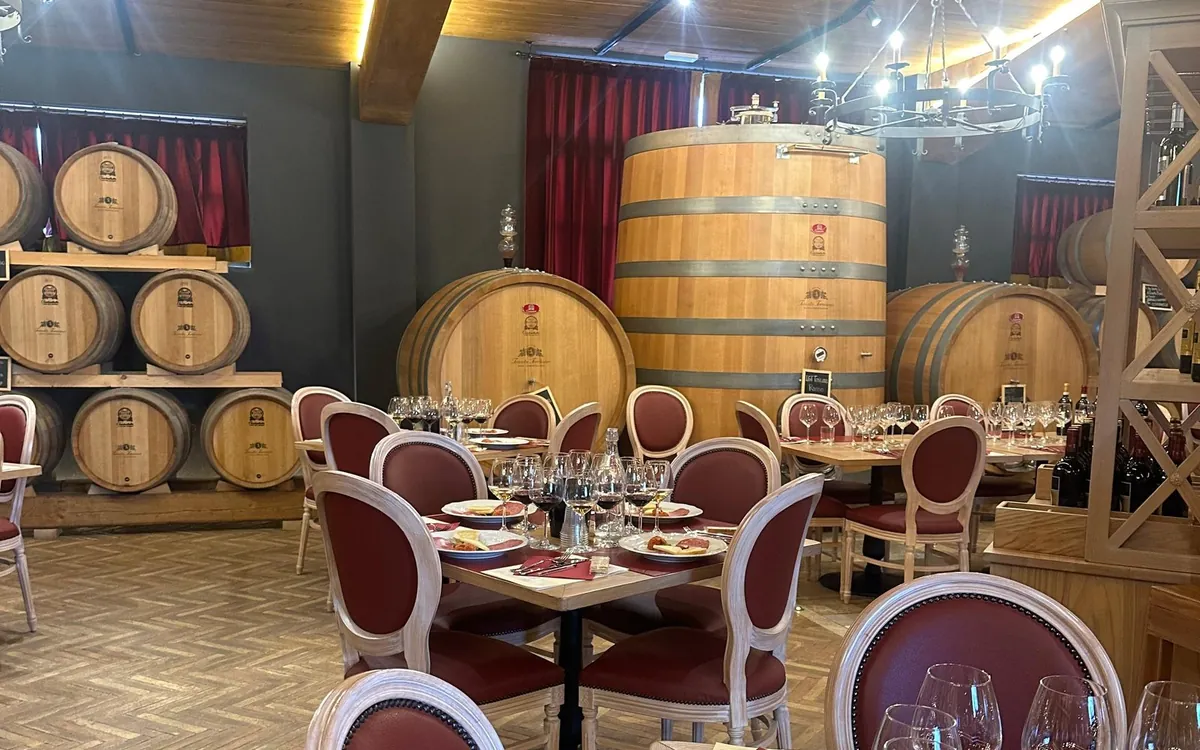 A tasting room lined with wine barrels, tables laid with glasses and plates